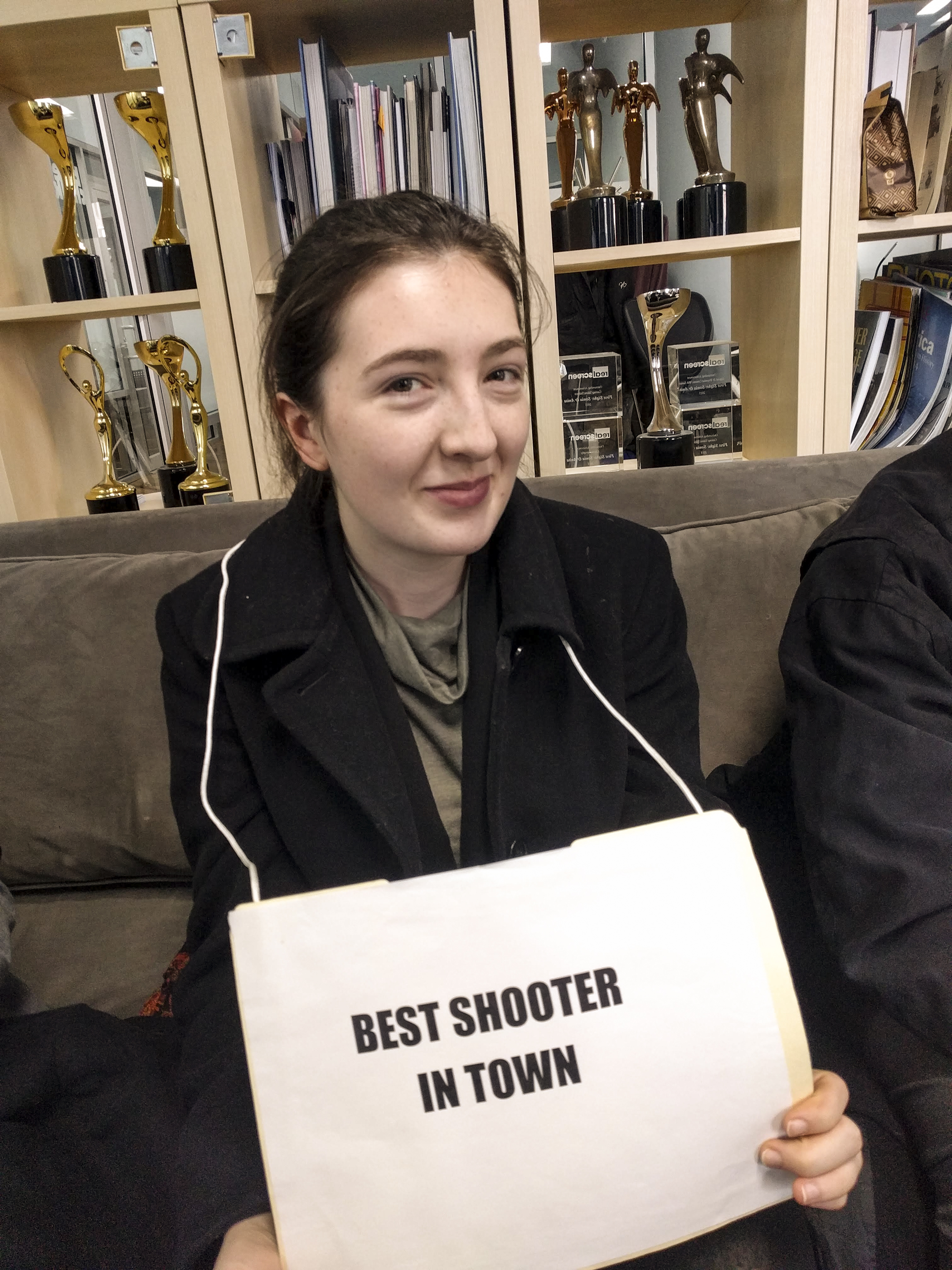 Catie Rafferty holds a sign that reads Best Shooter In Town.