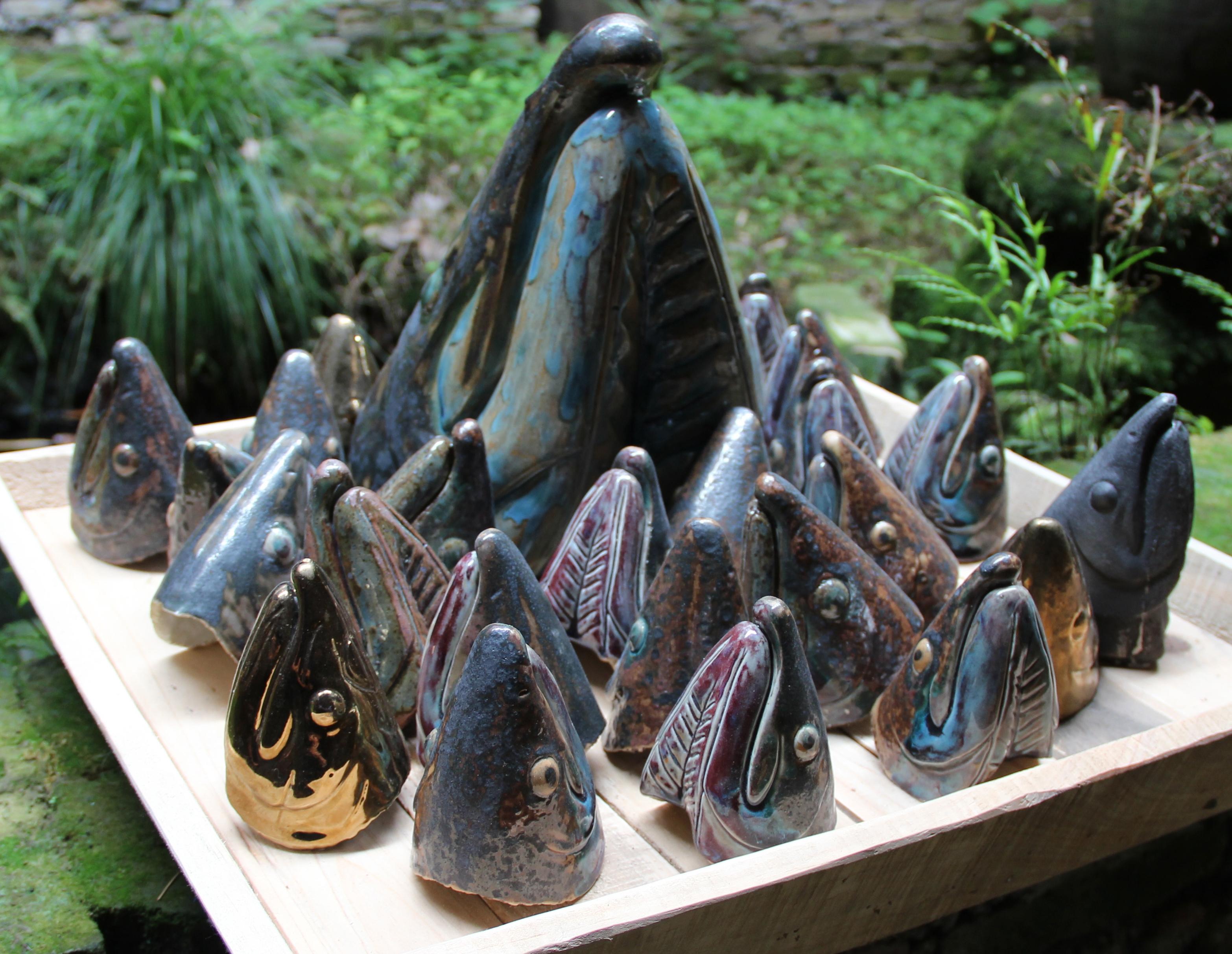 Many sculptures of fish heads sit on a surface.