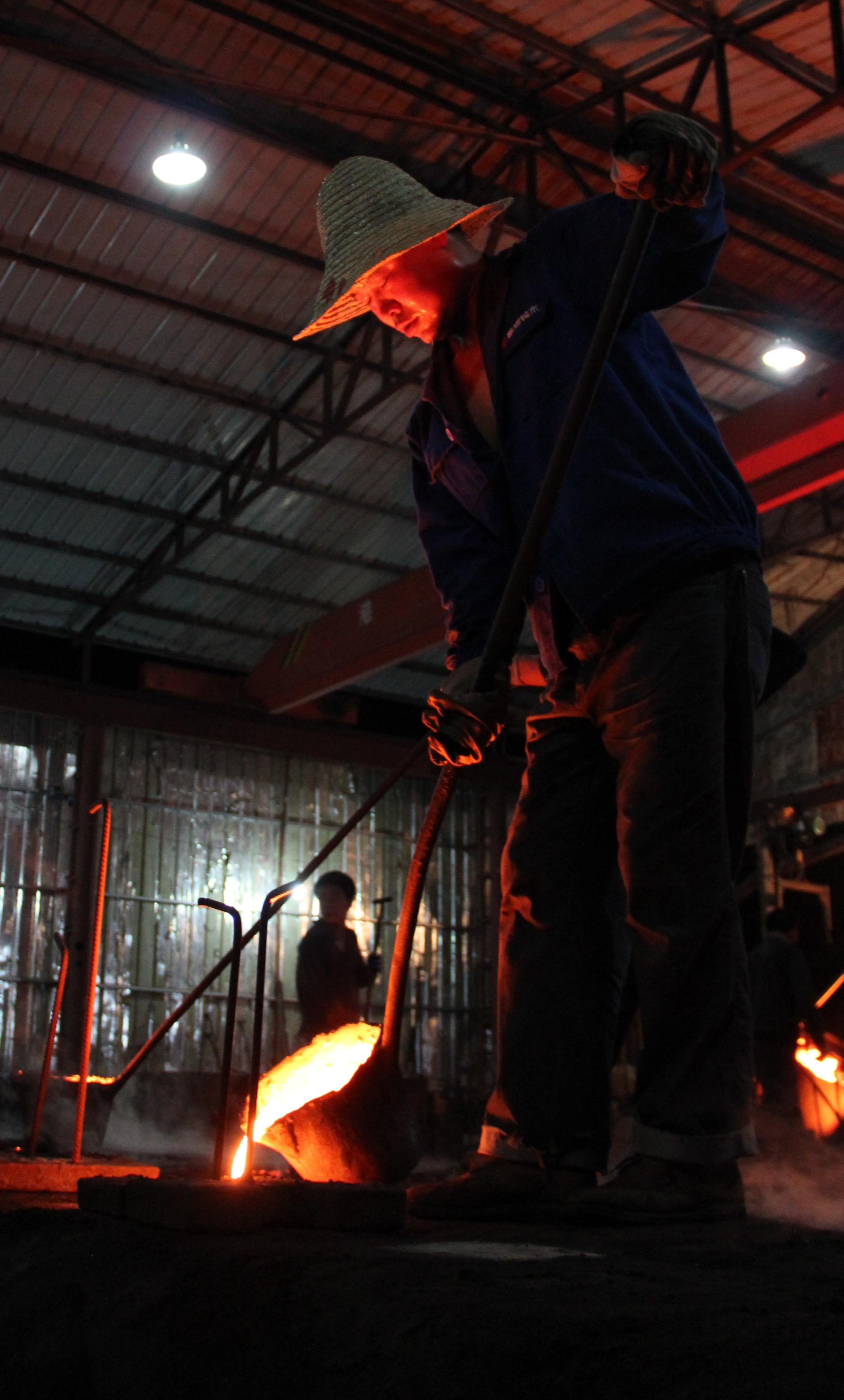 An artist pours hot iron in a foundry.