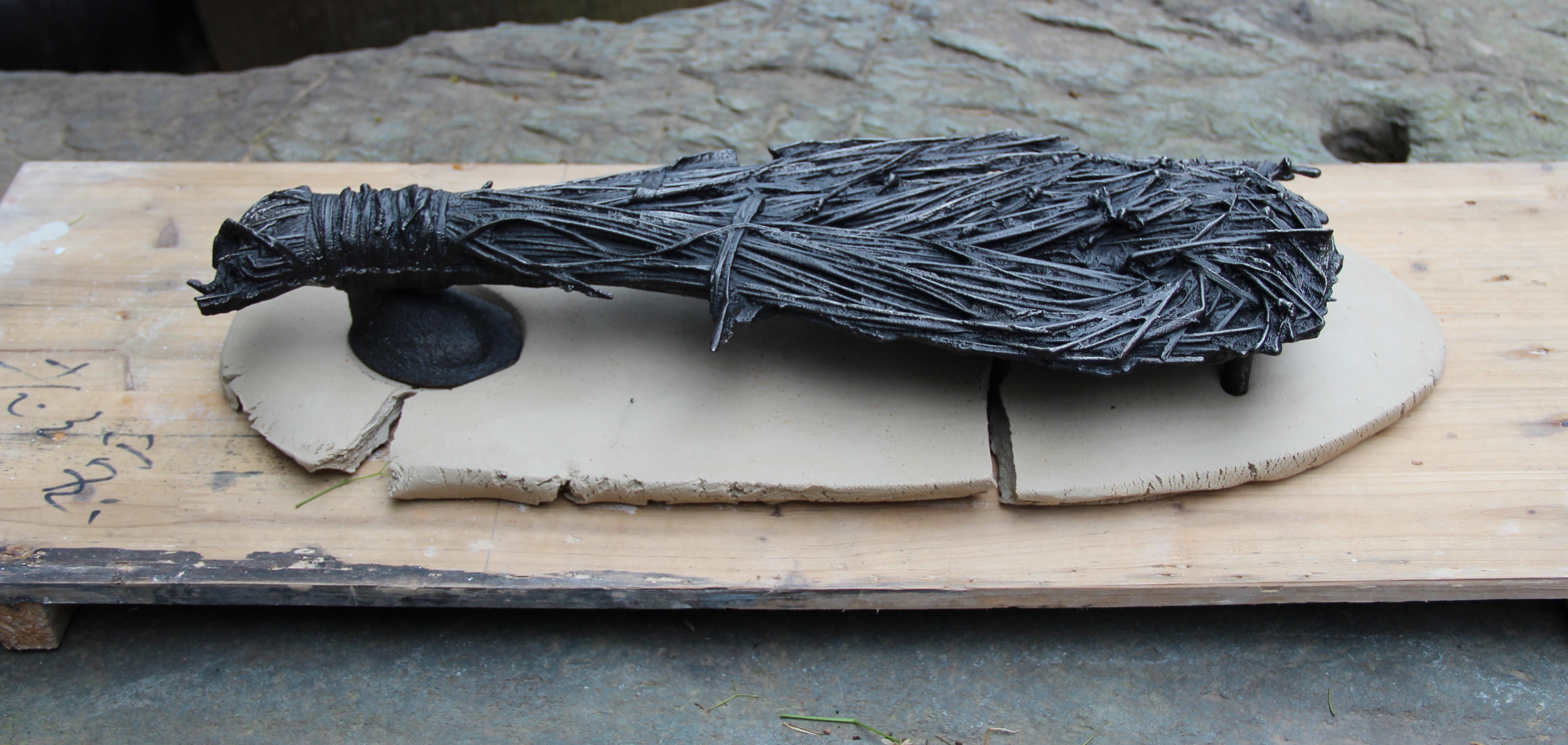 A sculpture that looks like a broom rests on a surface.