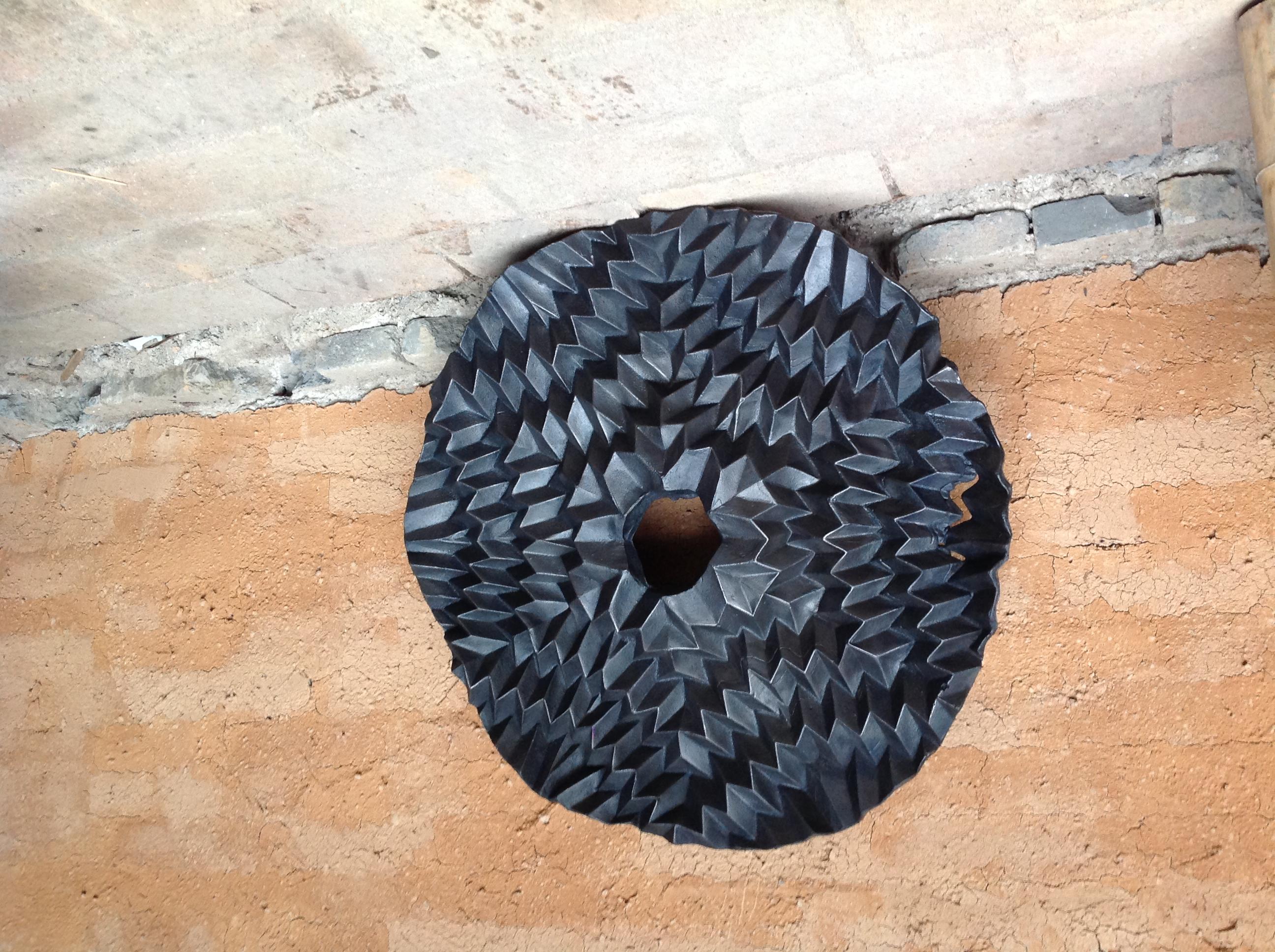 A black textured sculpture rests against the wall.