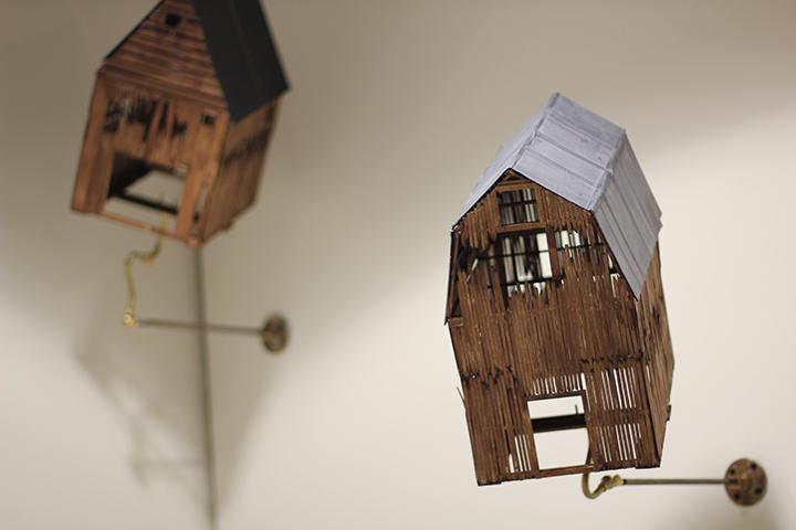 Wooden model houses hang on a wall.
