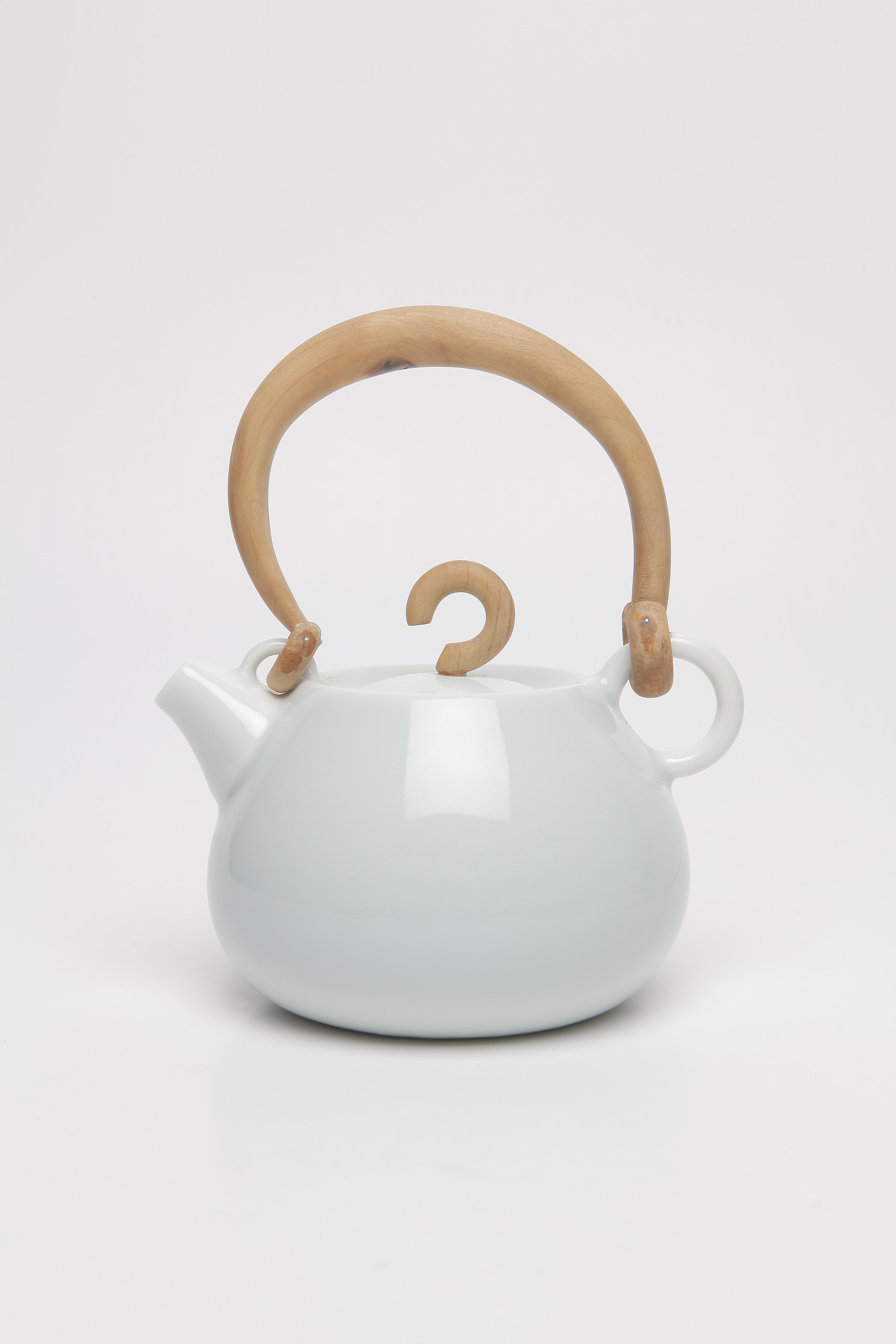 A ceramic teapot with an intricate handle.