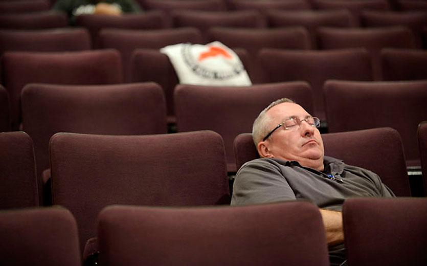 A man sleeps in an empty audience.