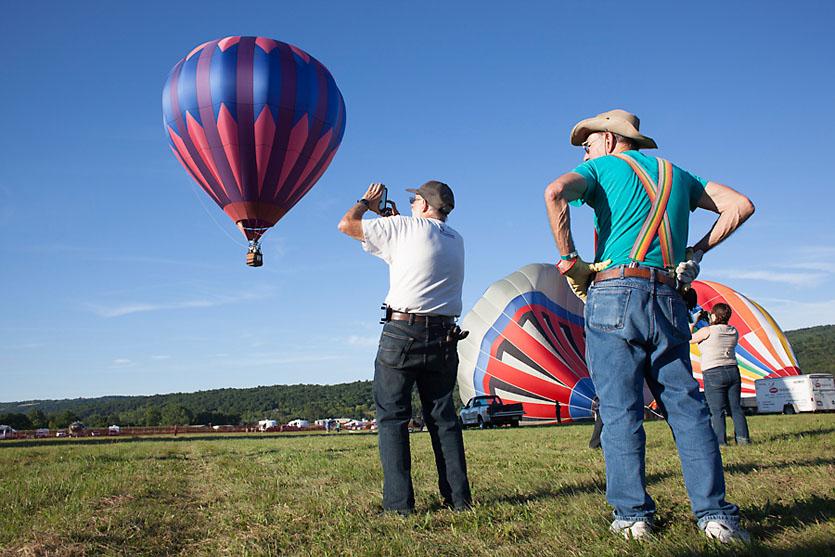 A man take a photo of a hot-air balloon taking off.