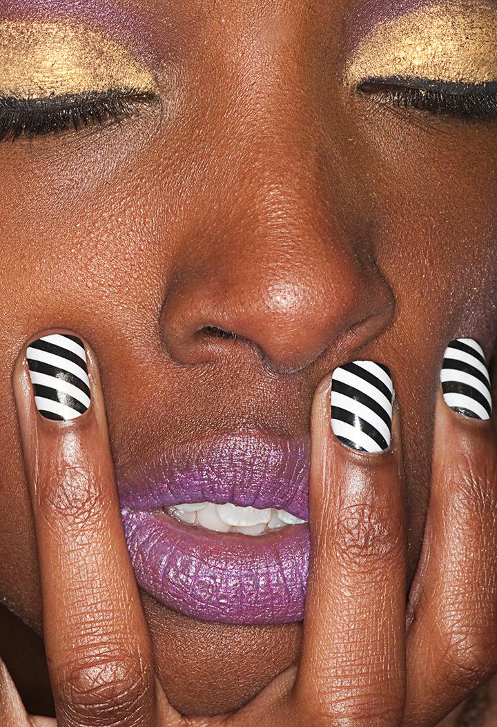 A detailed photo of a someone's face and their nails painted black and white.