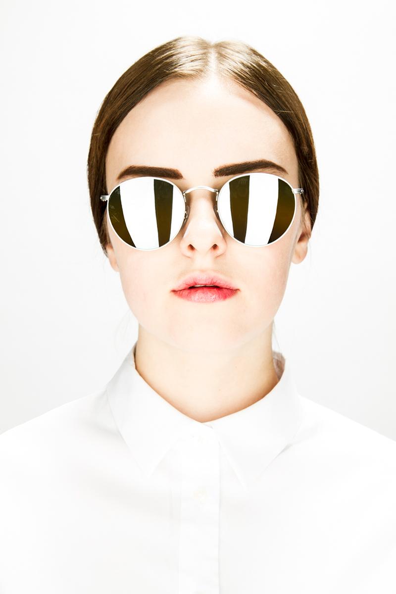 A portrait of a woman wearing reflective sunglasses.