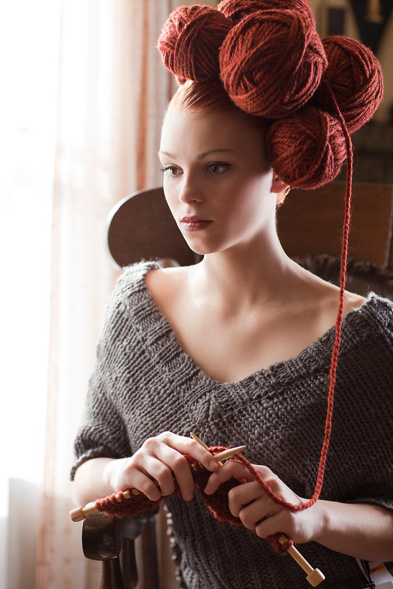 A photo of a woman wearing balls of yarn in her head.