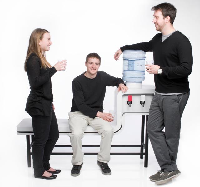 People hover around a bench-water cooler hybrid furnishing.