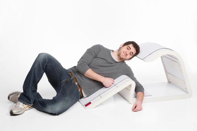 A person lies on a chair on his side.