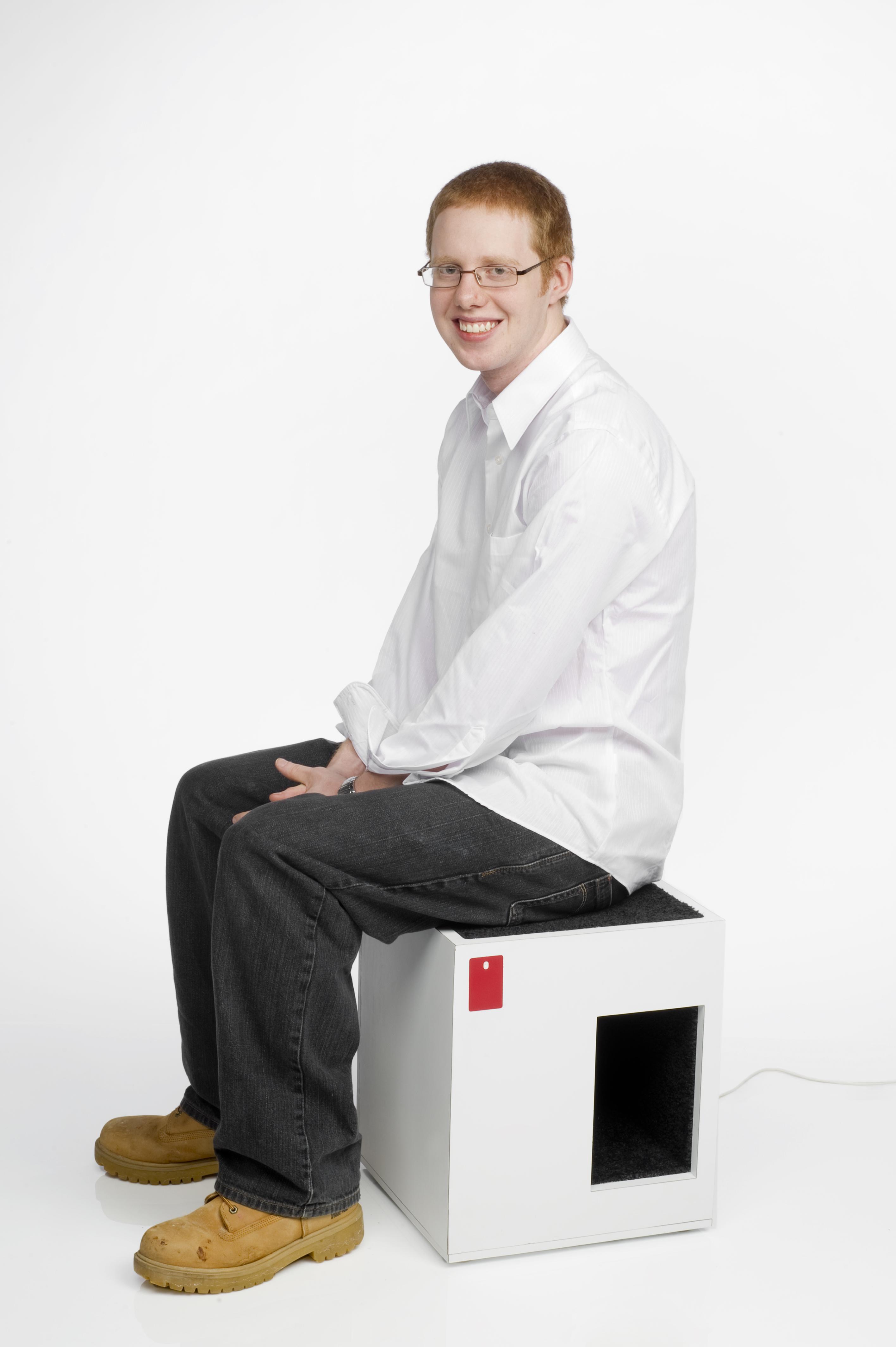 A person sits on a seat-litter box combo design