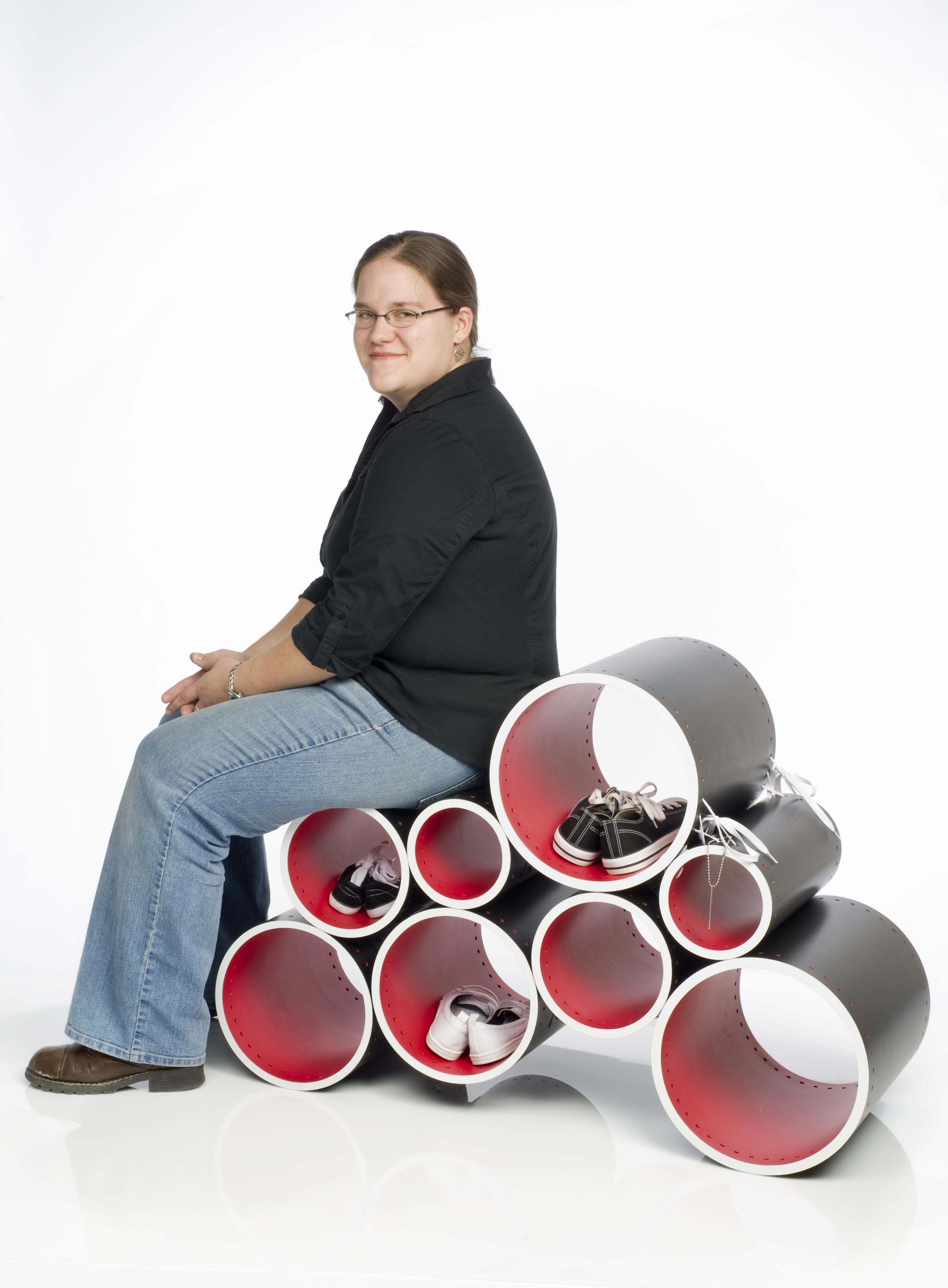 A person sits on a bench made of cylinder-shaped objects.