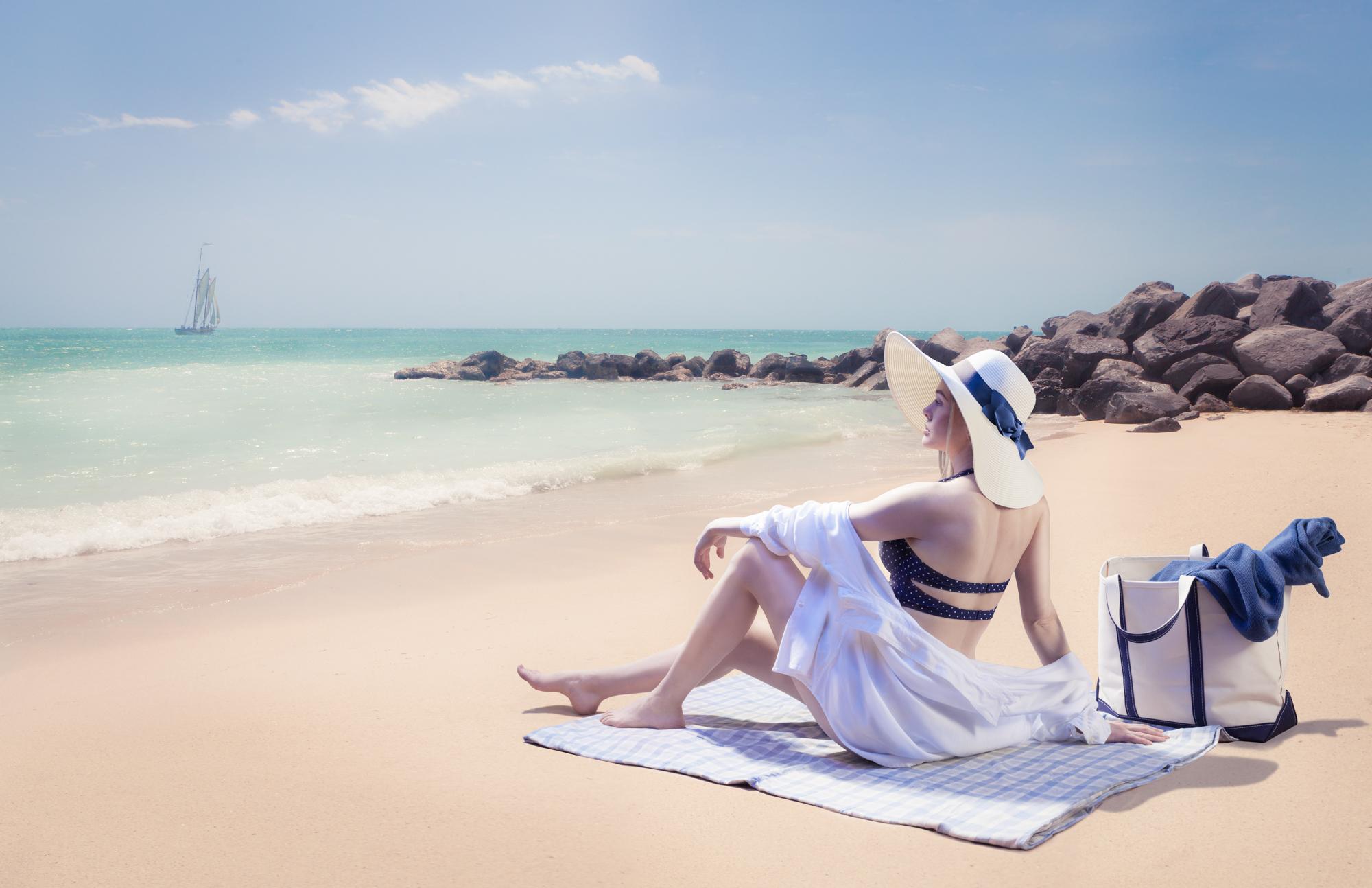 A woman sun bathes on the beach.